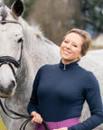 Woman standing next to a gray horse in an outdoor setting