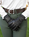 Person wearing black leather gloves with a blurred green background