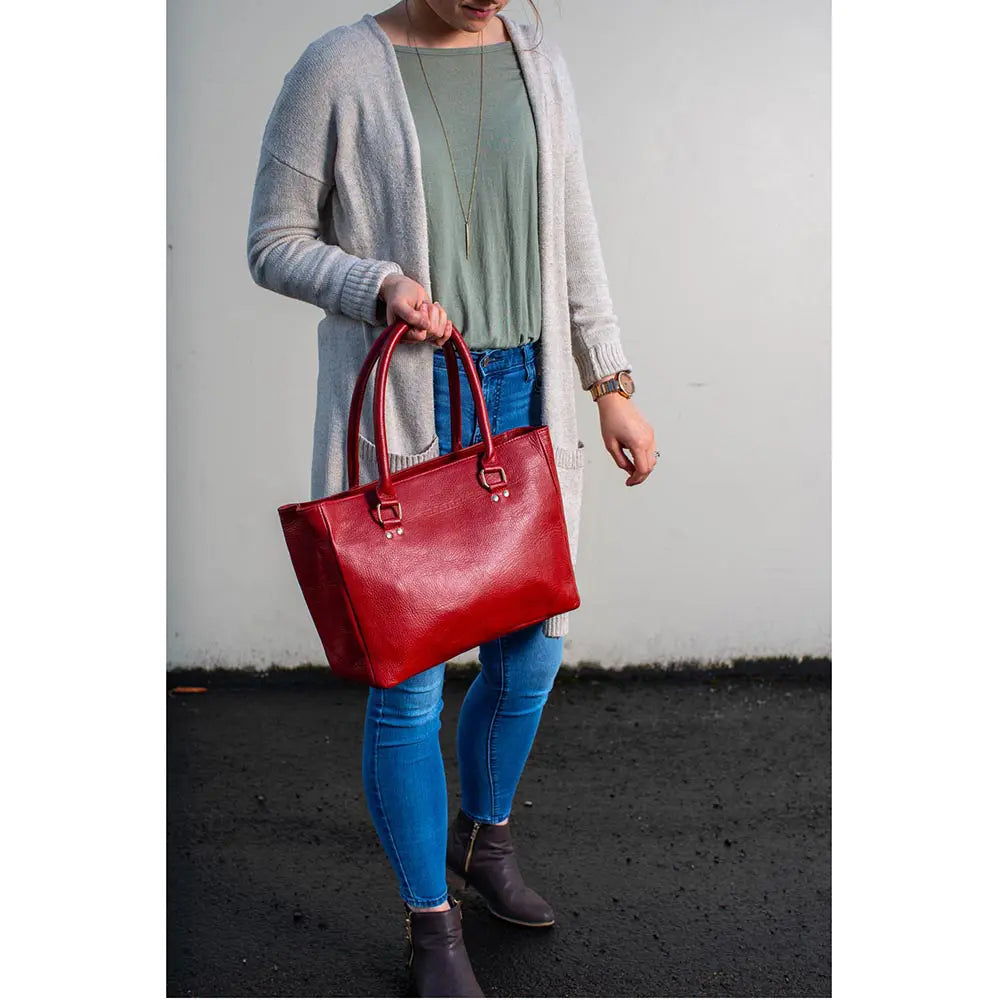 Person holding a red handbag against a plain background