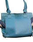 Blue handbag with a gun held by a hand on a white background