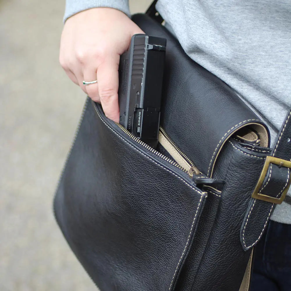 Person placing a phone into a black leather bag.