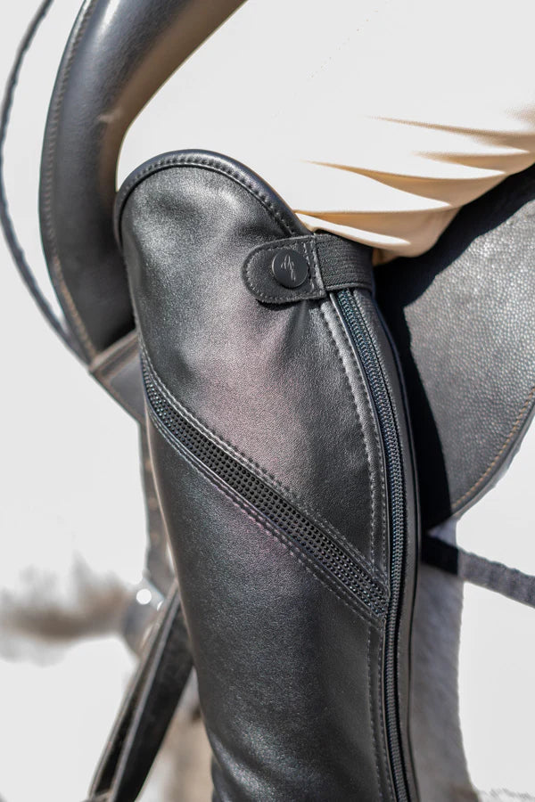 Close-up of a black leather gaiter on a horse's leg with a white background