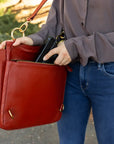 Person holding a red handbag with a blurred outdoor background