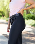 Person wearing black riding pants with a blurred green outdoor background