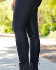 Person wearing black riding pants with a blurred natural background