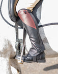 Close-up of a person wearing a riding boot with a stirrup on a horse.