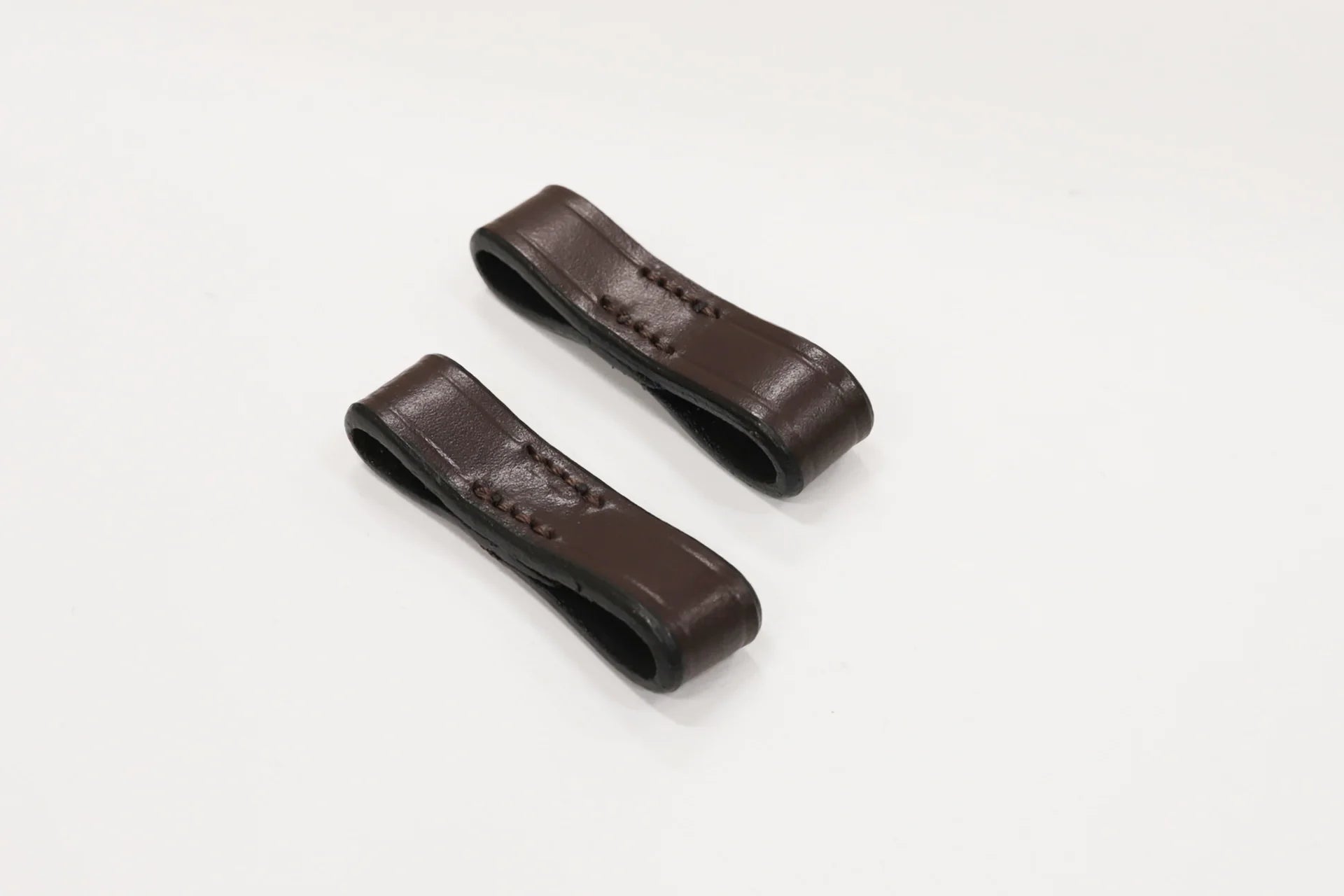 Two brown leather straps on a white background