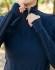 Person wearing a navy blue long-sleeve shirt with a zipper, outdoors.