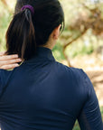 Person wearing a navy blue long-sleeve shirt with a blurred natural background
