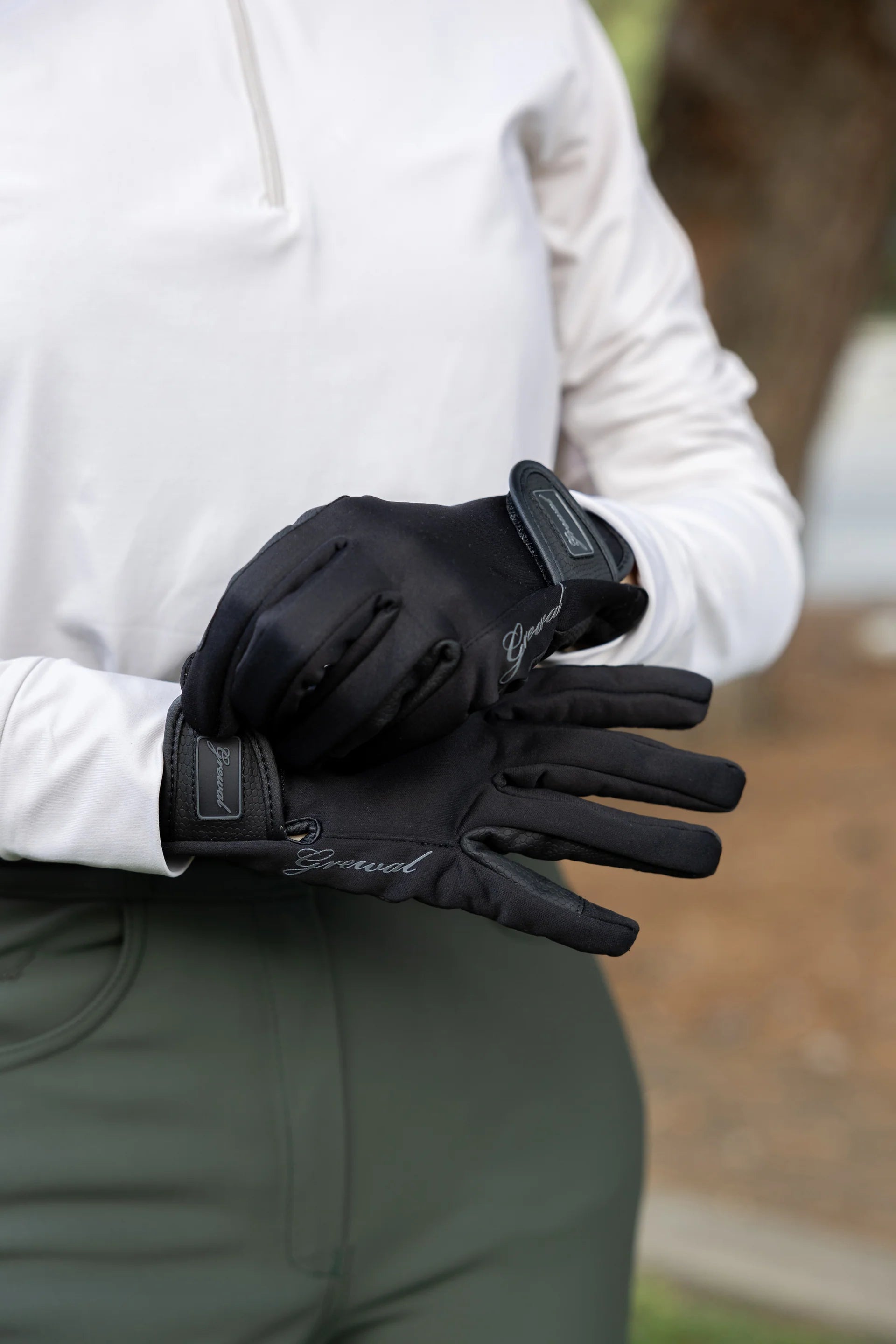 Person wearing black gloves with a brand logo, holding them out in front.