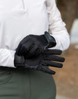 Person wearing black gloves with a brand logo, holding them out in front.