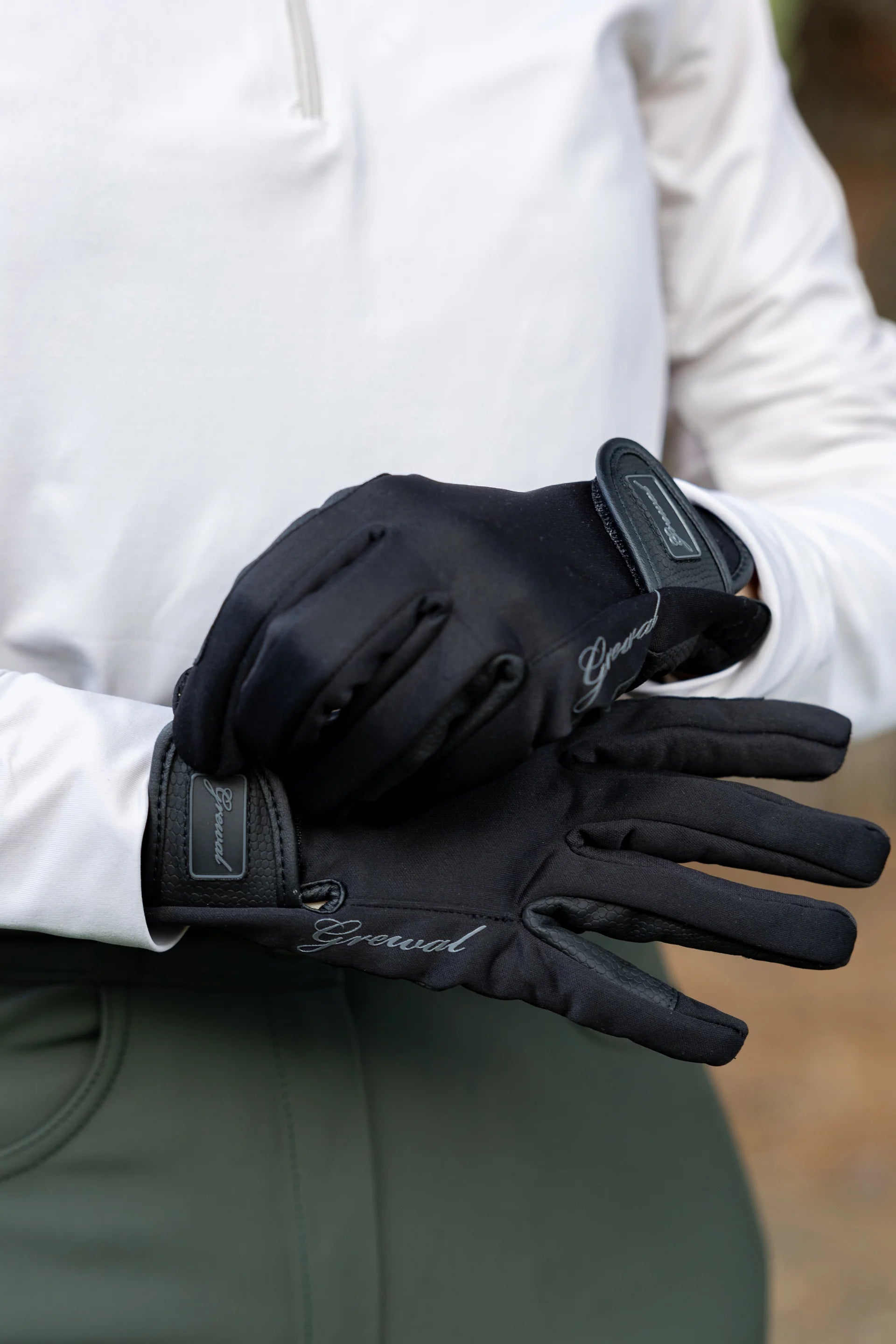 Person wearing black gloves with visible branding, holding a white jacket.