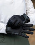 Person wearing black gloves with visible branding, holding a white jacket.