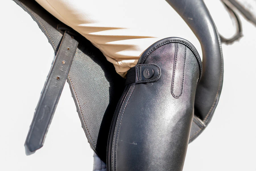 Close-up of a leather riding boot with a stirrup on a white background