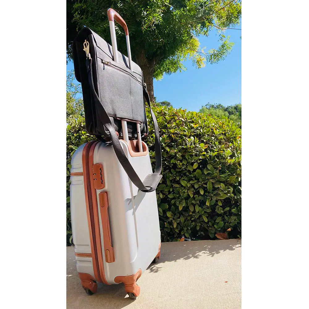 Two suitcases, one white with brown accents and one black, against a natural background.