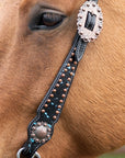 Close-up of a horse's eye with a decorative bridle strap.