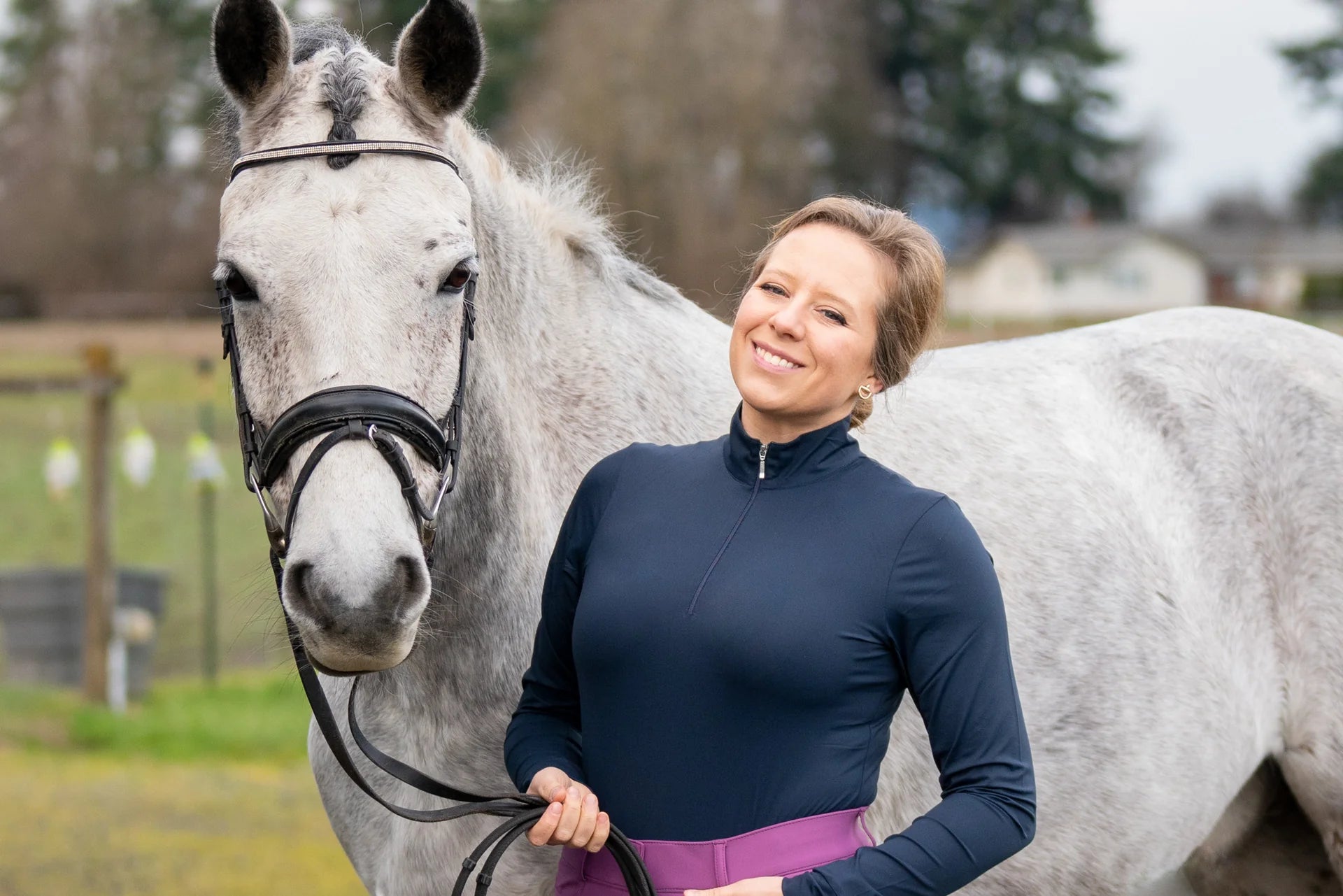 Woman standing next to a gray horse in an outdoor setting