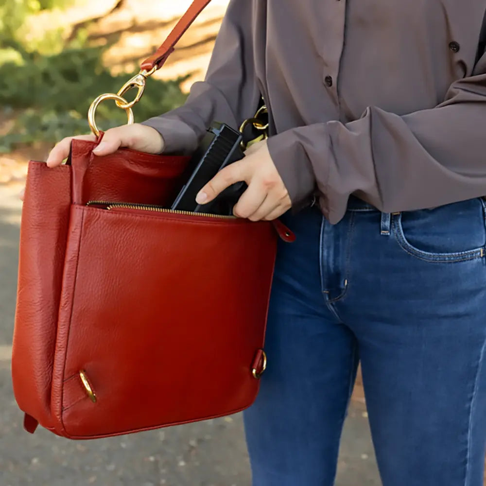Person holding a red handbag with a blurred outdoor background