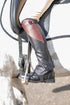 Close-up of a person wearing a riding boot with a stirrup on a horse.