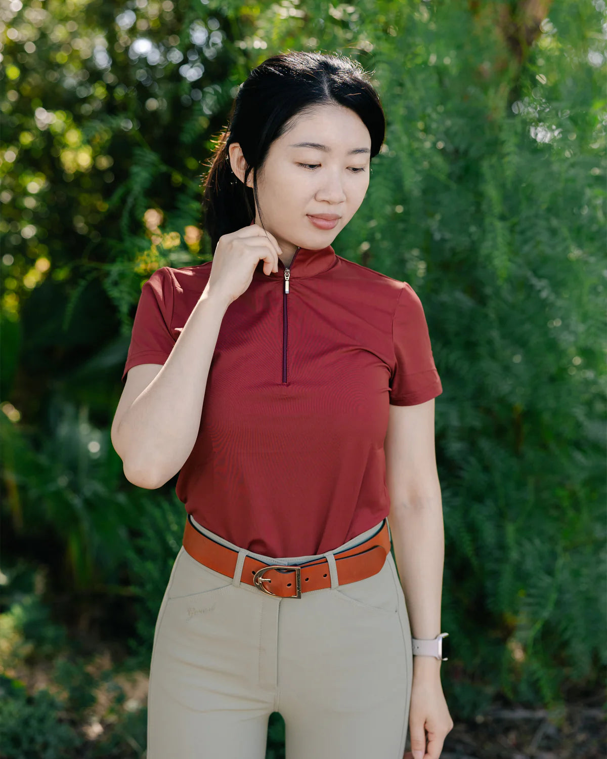 Woman wearing a red Aerocool Short Sleeve Shirt and beige breeches 