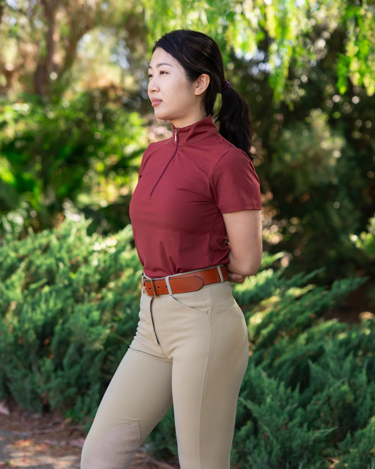 Woman in equestrian attire standing in a natural setting